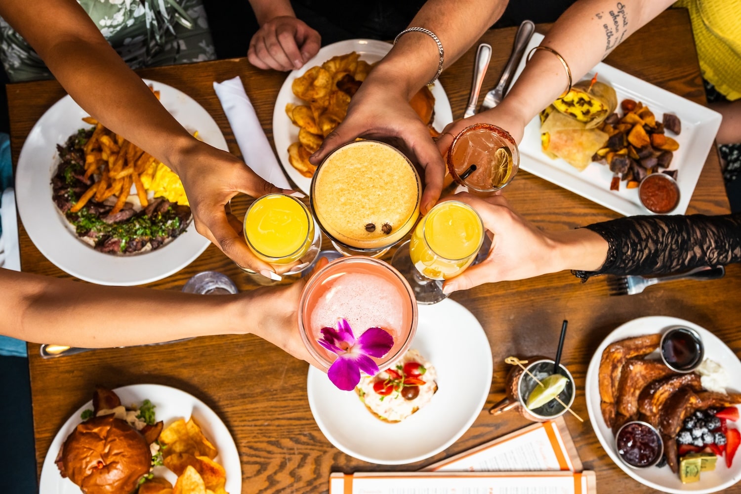 Displaying an assortment of brunch items on the table while a toasting cocktails.